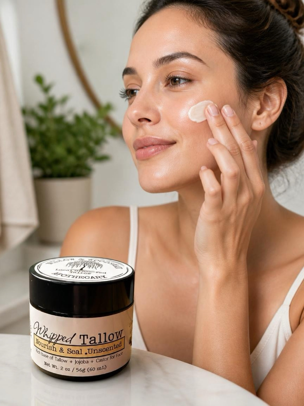 Woman applying Nourish & Seal Whipped Tallow balm to face